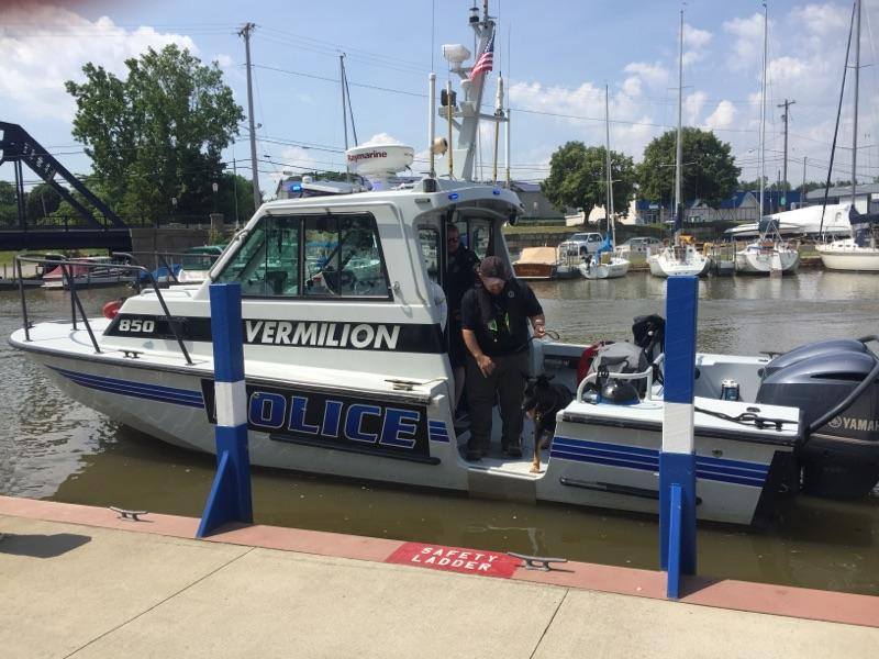 police boat at dock with policeman and k9