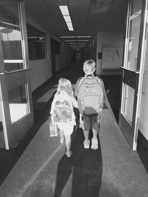 the back of two childrent walking into school