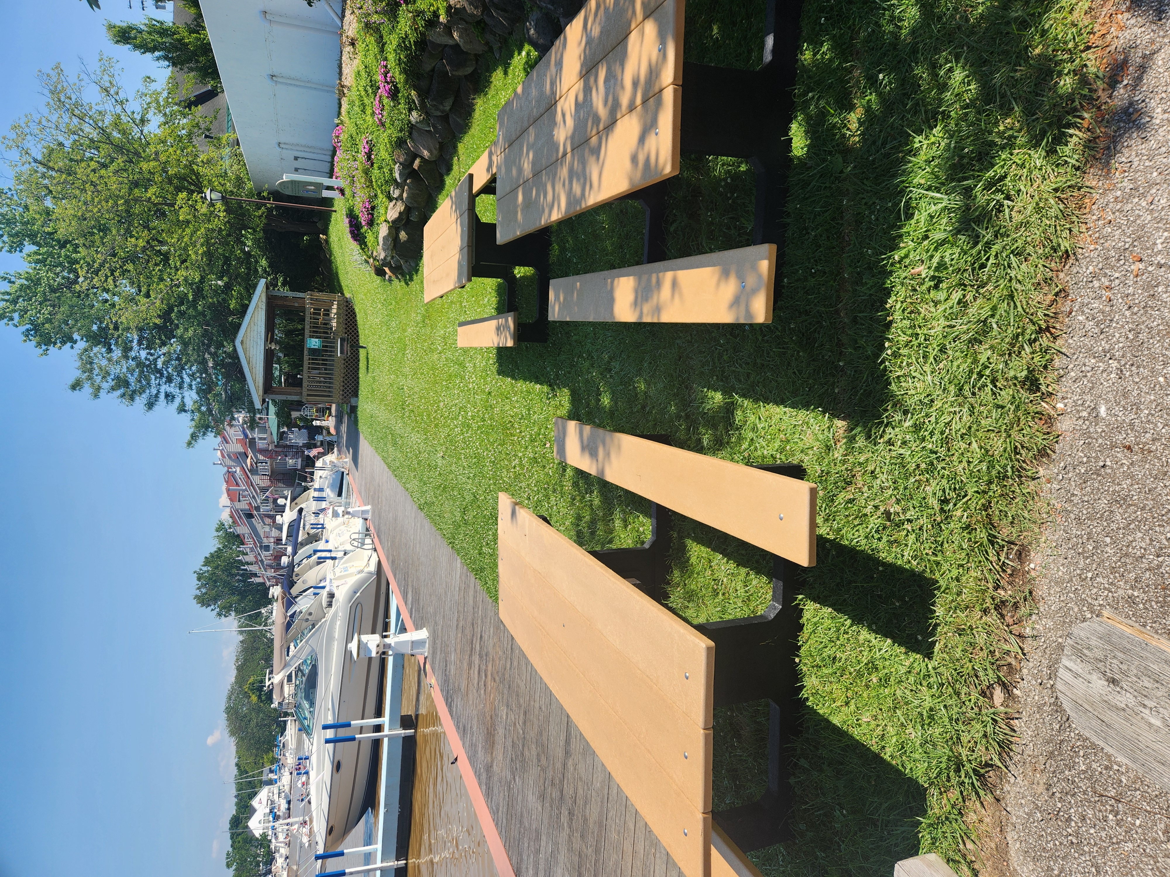 picnic tables at marina on the river with boats in the background