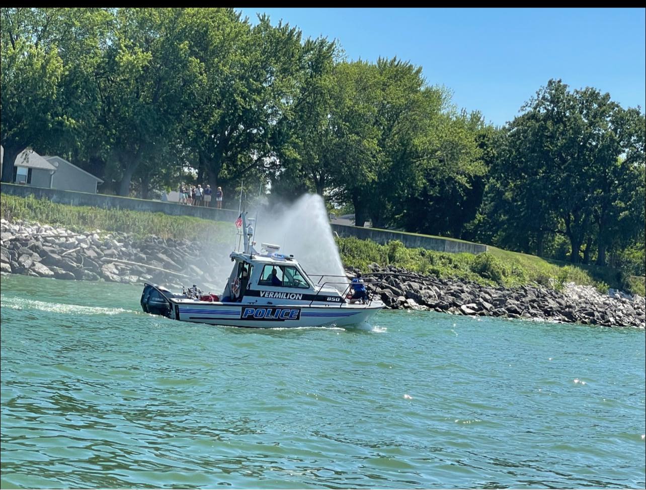 police boat spraying water onto shore as people watch