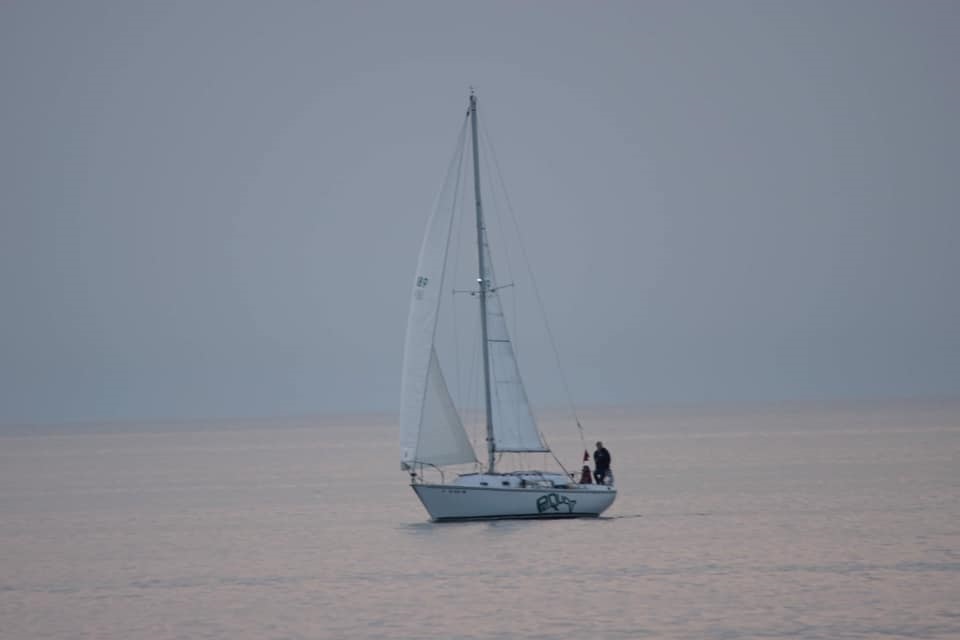 Sailboat on the lake with no waves and grey sky